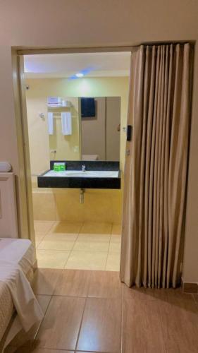 a bathroom with a large mirror and a sink at Jandaia Hotel Campo Grande in Campo Grande