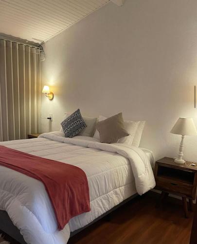 a bedroom with a large bed with white sheets and pillows at Pousada Villa Tiradentes Suítes - Centro in Tiradentes
