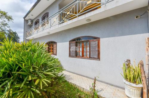 a white house with windows and a balcony at Casa do Loro Hospedagem in Curitiba