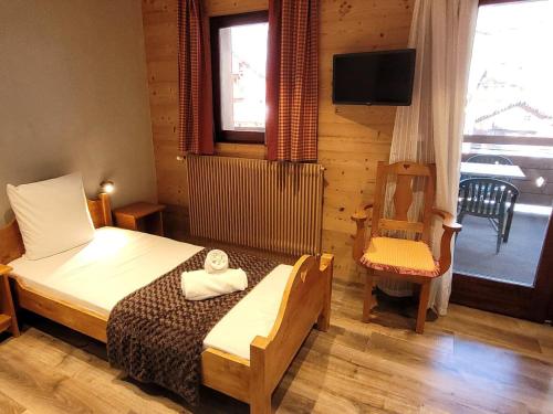 ein Schlafzimmer mit einem Bett, einem Fernseher und einem Stuhl in der Unterkunft Appartement rénové, proche pistes, balcon, 3 chambres, parking, Wifi inclus - FR-1-598-132 in Les Gets
