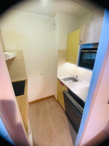 une petite cuisine avec un évier et un micro-ondes dans l'établissement Charmant appt 2 Ch St Jacques, à La Plagne Tarentaise