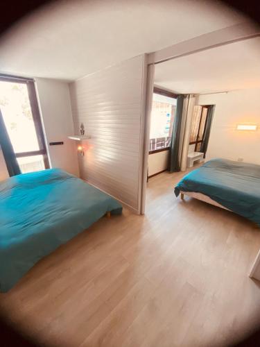 une chambre avec deux lits et une grande fenêtre dans l'établissement Charmant appt 2 Ch St Jacques, à La Plagne Tarentaise