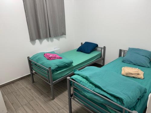 deux lits dans une chambre avec des draps verts dans l'établissement Appartement G, RESIDENCE DU RENOUVEAU, Stade de France, idéal pour 4 pers, à Saint-Denis
