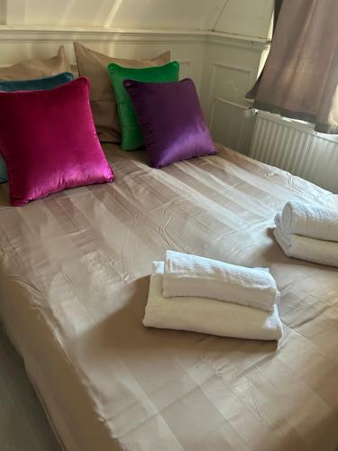 a bed with purple and green pillows and towels on it at Cosy by Mandy in Amsterdam