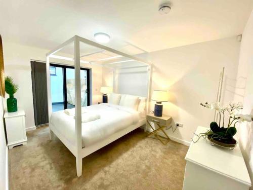 a white bedroom with a white canopy bed at Ranmoor Serviced Apartments at Wilkinson Lane - The Sandford Suite in Sheffield