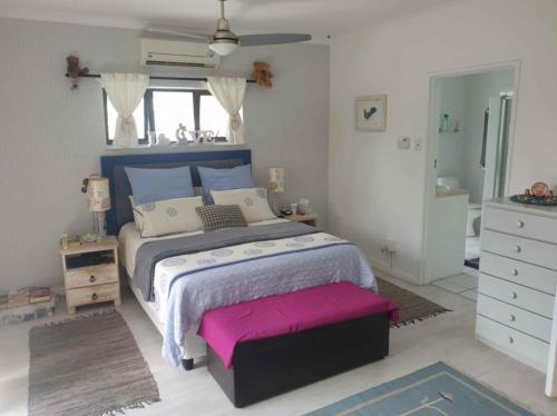a bedroom with a large bed with a pink seat at Paradise in Plettenberg Bay in Plettenberg Bay