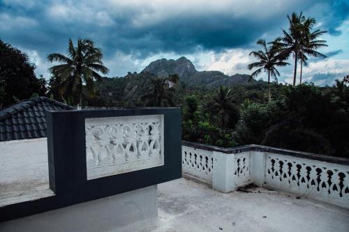 a white fence with palm trees and mountains in the background at The Fika Casa Home Stay in Meenangadi