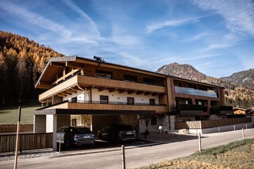 a building with two cars parked in front of it at Jaggling Appartements in Sankt Ulrich am Pillersee