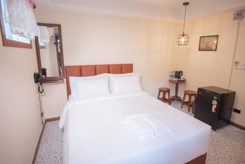 a bedroom with a large white bed and a table at JB Home Bangkok - Victory monument in Bangkok