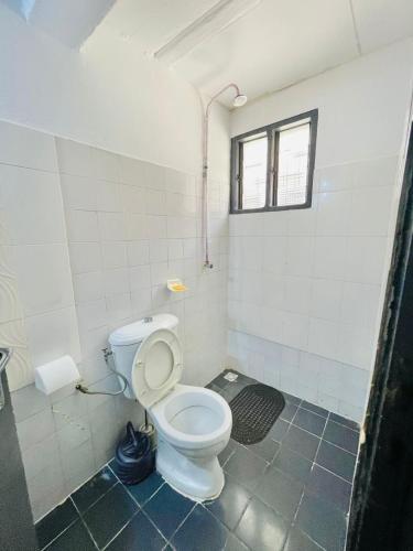 Un baño con inodoro blanco y ventana. en Appartement Grace, en Abiyán