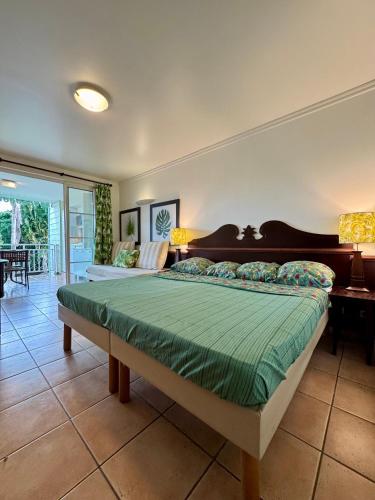 a bedroom with a large bed with a green comforter at Kaz Caraïbes, piscine & plage in Sainte-Luce