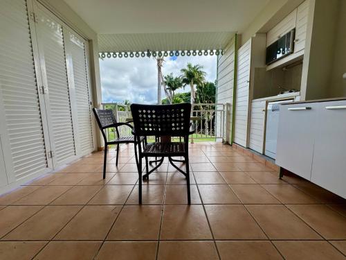 a porch with two chairs and a table and a balcony at Kaz Caraïbes, piscine & plage in Sainte-Luce