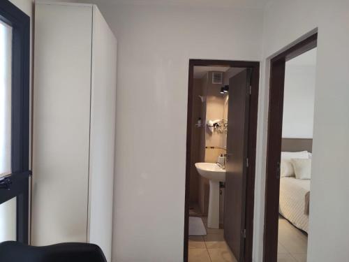 een badkamer met een wastafel, een bed en een spiegel bij 3 Personas - Balcon, Wifi & Cafe in Santiago del Estero