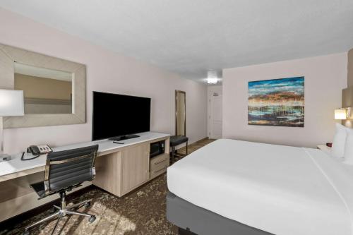 a hotel room with a bed and a desk with a television at Best Western Worlds Of Fun in Kansas City