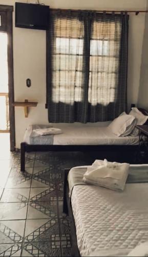 two beds in a room with a window at Trem de Pouso Rustic Guest House in Tiradentes
