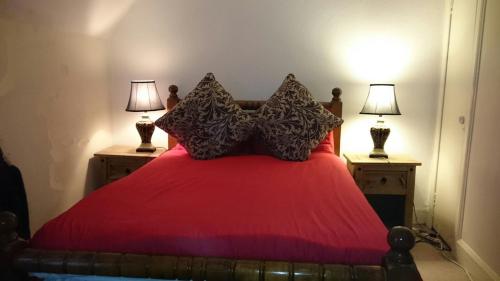 a bedroom with a red bed with two lamps at Royal Mile Budget Apartments in Edinburgh