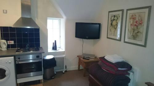 a kitchen with a couch and a tv on the wall at Royal Mile Budget Apartments in Edinburgh