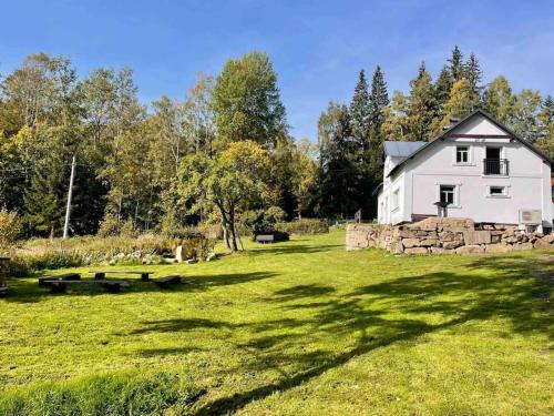 a white house in a field with a stone wall at Vila 100klasa in Nejdek