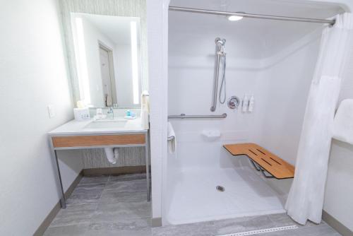 a white bathroom with a shower and a sink at Hilton Garden Inn Lakewood in Lakewood