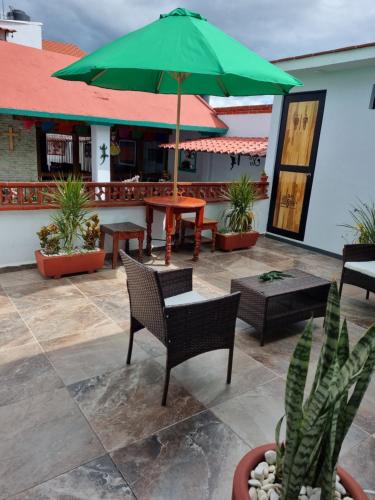a patio with chairs and a green umbrella at CASA JOAQUÍN HOSTAL in Oaxaca City