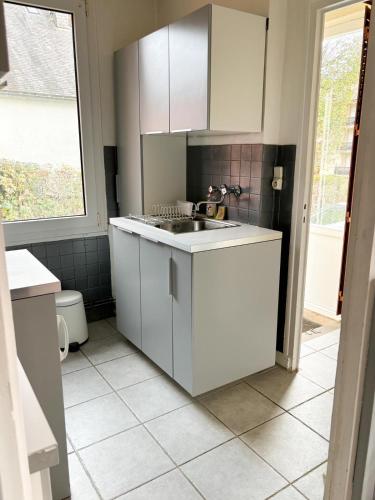 une cuisine avec des armoires blanches et un évier dans l'établissement La Petite Maison, à Murat-le-Quaire