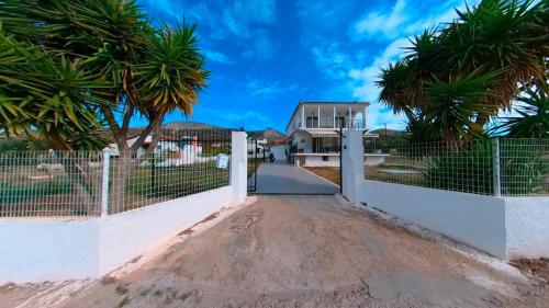 a house with a fence and palm trees at Villa Aelia Luxury Maisonette in Salamís