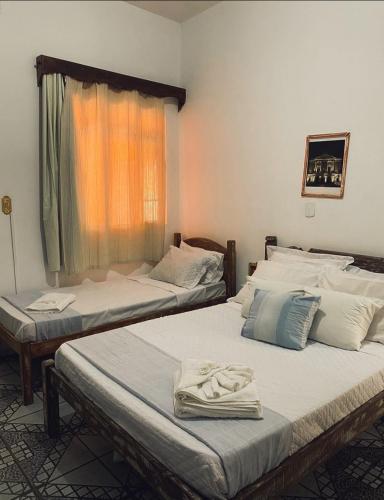 two twin beds in a room with a window at Trem de Pouso Rustic Guest House in Tiradentes