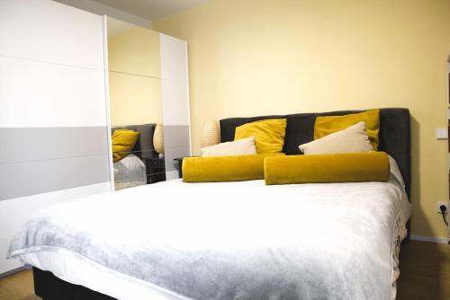 a bedroom with a bed with yellow pillows and a mirror at Cozy Stylish Studio near Luxembourg City Centre in Luxembourg