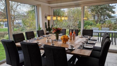 a dining room with a table and chairs and large windows at Ferienhaus Blütenlodge Bodensee in Lindau-Bodolz