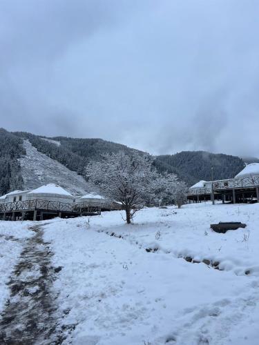 a field covered in snow with buildings and trees at Ethno complex Ala kuch in Kaindy