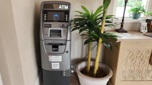 an atm machine sitting next to a potted plant at La Quinta Inn by Wyndham Clute Lake Jackson in Clute
