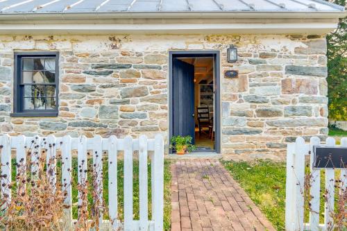 a stone house with a blue door and a white fence at Historical Thurmont Escape with Furnished Deck! in Thurmont