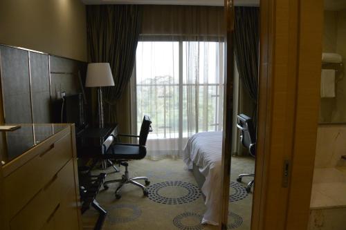 a hotel room with a bed and a desk and a window at Hotel Anda China Malabo in Malabo