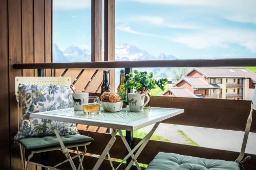 d'une table sur un balcon avec vue sur les montagnes. dans l'établissement Slow Chalet Etale Ski in-out Duplex Mountain View Balcony & Free parking, à Manigod