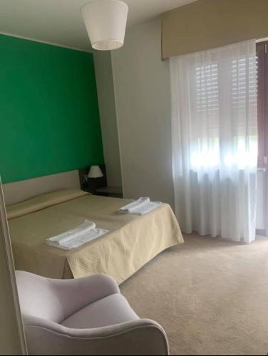 a room with a bed with a green wall and a chair at hotel lido in Viverone