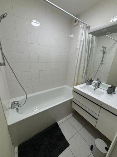 a white bathroom with a tub and a sink at F2 rénové lumineux dans résidence avec balcon et parking in Talange