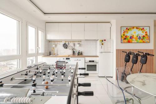 Il comprend une grande cuisine blanche avec une table et un réfrigérateur. dans l'établissement Nice Apartment with amazing view of Paris with private Parking, à Paris