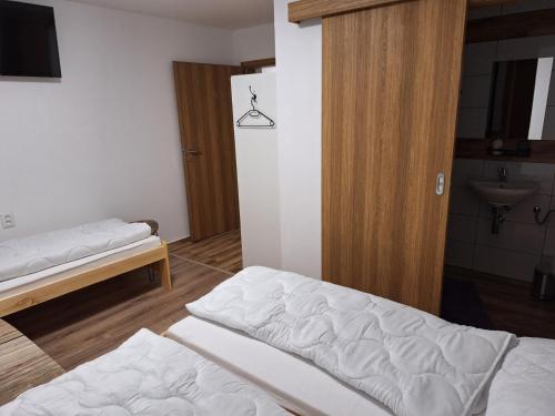 a room with two beds and a bathroom with a sink at BUBO Penzion & Restaurant in Moravany