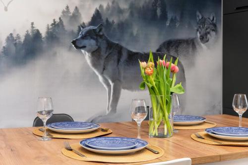 a table with plates and wine glasses and a wolf mural at Dablin 9 in Korbielów