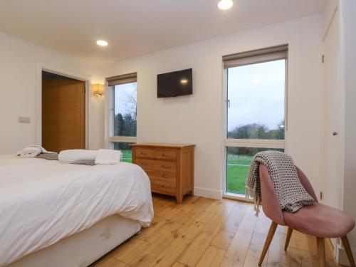 Un dormitorio con una cama y una silla y ventanas. en Oak, en Truro