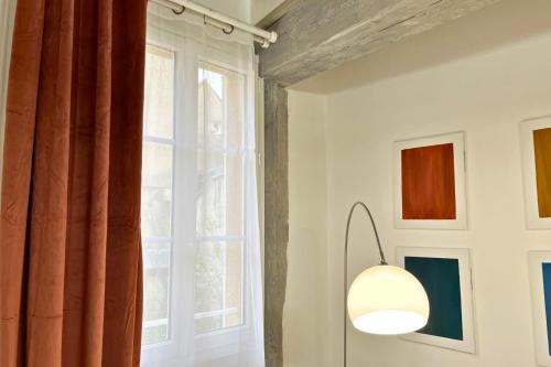 a light fixture in a room with a window at Henri en scène - Charme & Confort en Hypercentre Chartres - Au pied de la Cathédrale in Chartres
