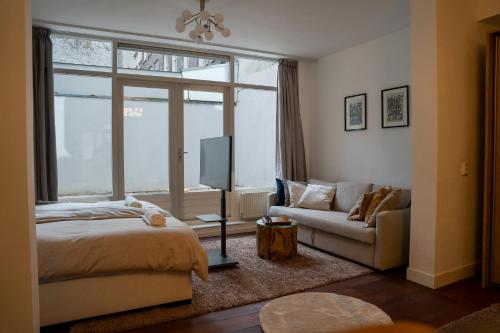 a bedroom with a bed and a tv and a couch at Skinny Bridge Boutique Stay in Amsterdam
