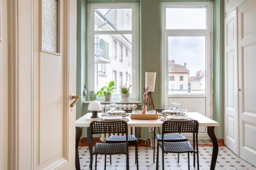 une salle à manger avec une table, des chaises et des fenêtres dans l'établissement Studio cosy- Calme et confort au cœur de Mulhouse, à Mulhouse