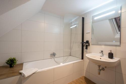 a white bathroom with a sink and a bath tub at Sali Homes Übernachten im Kulturdenkmal - Weinort in Besigheim