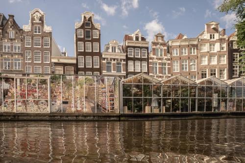 a greenhouse in front of buildings next to a river at Skinny Bridge Boutique Stay in Amsterdam