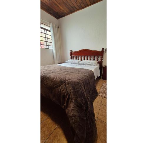 a bedroom with a bed and a window at Kitnet perto da rodoviária Campos do Jordão in Campos do Jordão