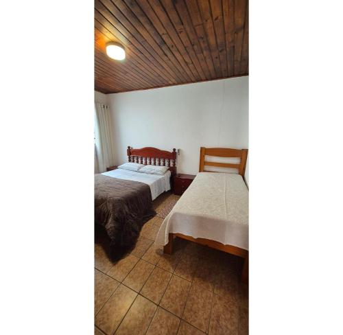 a bedroom with two beds and a wooden ceiling at Kitnet perto da rodoviária Campos do Jordão in Campos do Jordão