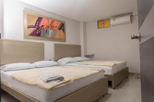 two beds in a bedroom with a painting on the wall at HOTEL DASANTO HD in Barranquilla