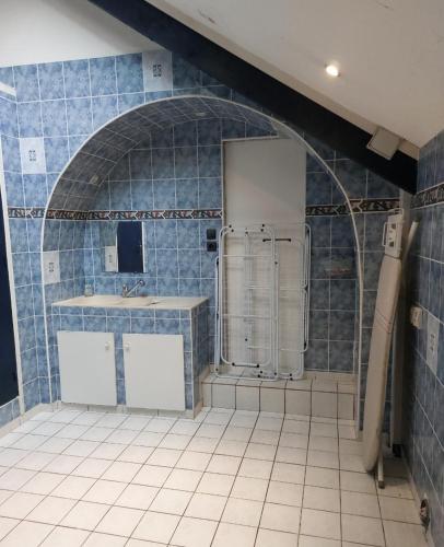 La salle de bains est pourvue de carrelage bleu, d'un réfrigérateur et d'un évier. dans l'établissement L'ABulle glanoise, à Gland