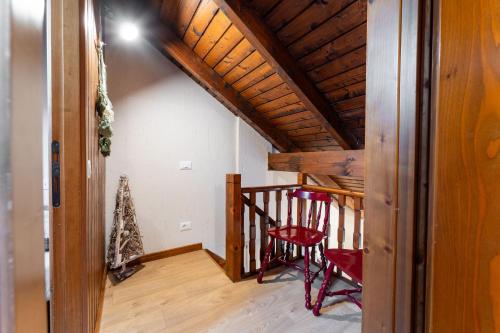 a room with a wooden staircase with a red chair at 3 Minuti da Asiago - Zona Tranquilla e Silenziosa in Gallio